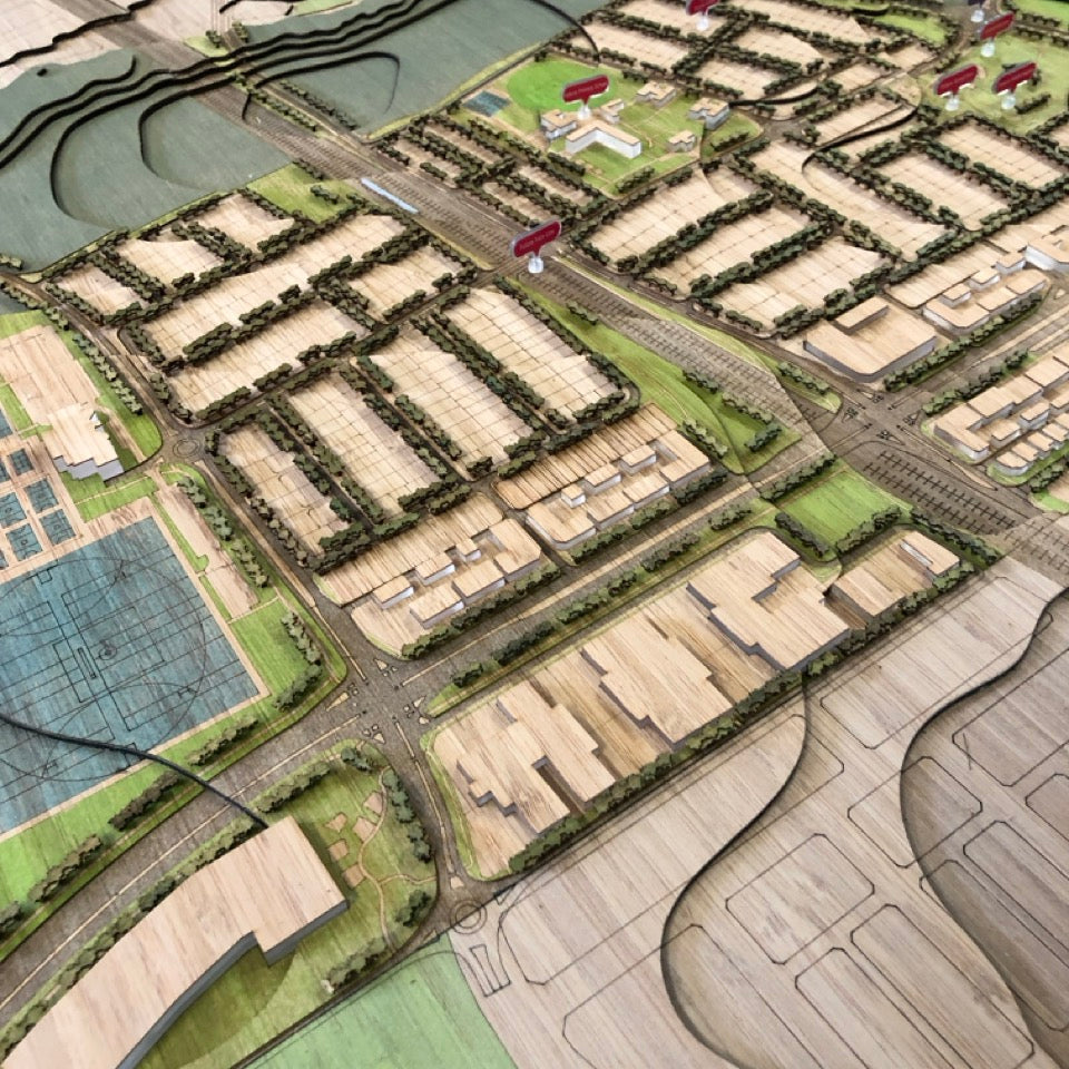 Architectural scale model of a planned urban neighborhood with roads, buildings, and green spaces for development display.