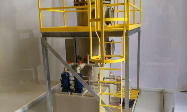 Architectural model featuring industrial equipment, yellow railings, vertical ladder, valves, and blue machinery on platform.