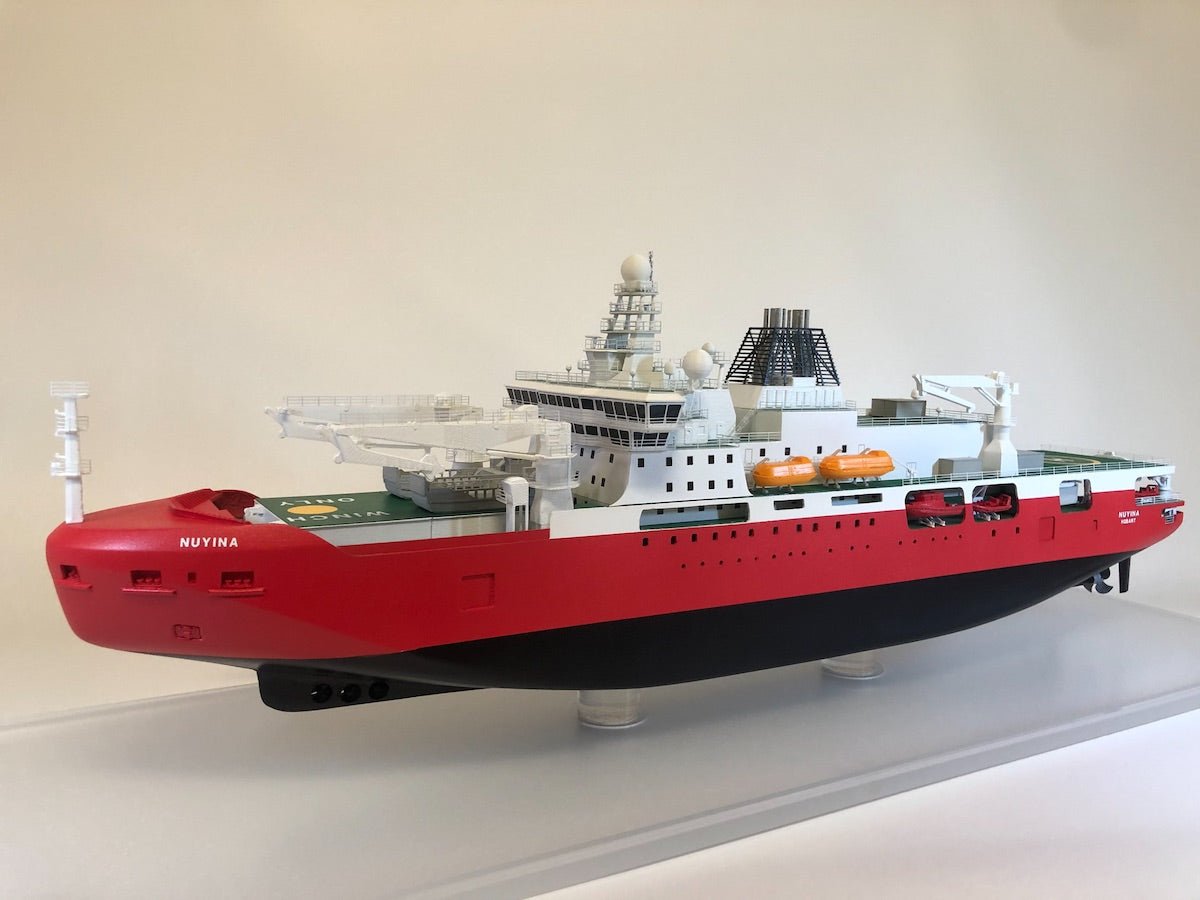 RSV Nuyina maritime ship scale model by The Model Shop, in red and white, showcased on a transparent display stand.